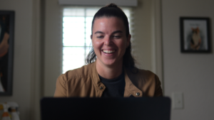 Speaking Business Coach, Taylor Lunin, sitting at her computer and smiling.